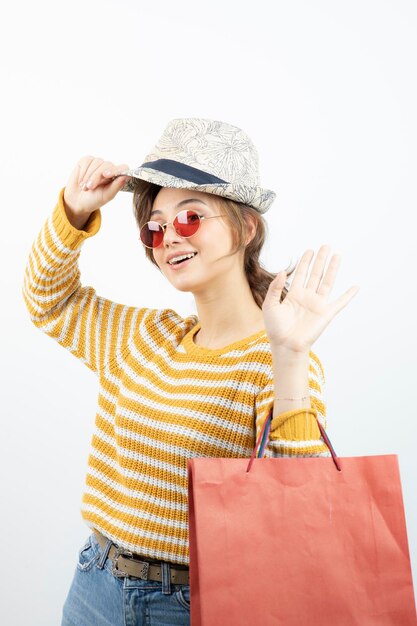 Foto einer jungen brünetten Frau mit Sonnenbrille, die eine Einkaufstasche hält. Foto in hoher Qualität