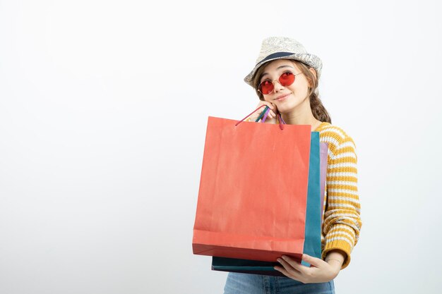 Foto einer jungen brünetten Frau mit Sonnenbrille, die Einkaufstüten hält. Foto in hoher Qualität