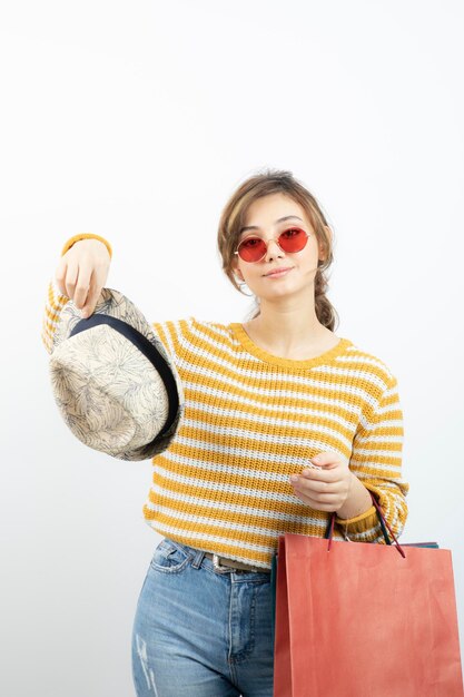 Foto einer jungen brünetten Frau mit Sonnenbrille, die Einkaufstüten hält. Foto in hoher Qualität