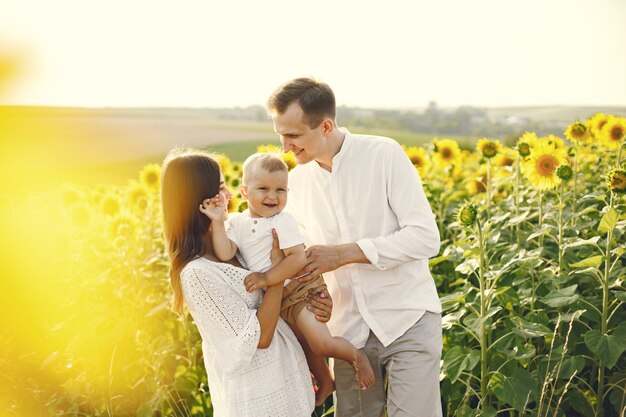 Foto einer jungen Familie am Sonnenblumenfeld an einem sonnigen Tag.