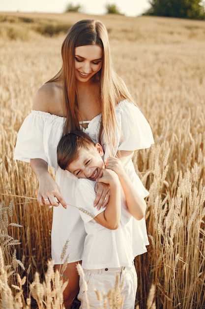 Foto einer jungen Familie, die an einem sonnigen Tag auf dem Weizenfeld steht.