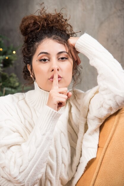 Foto einer jungen Frau, die in einem bequemen Stuhl in der Nähe des Weihnachtsbaums sitzt