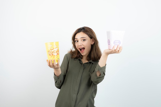 Foto einer jungen Frau in lässigem Outfit mit stehenden Popcorn-Boxen. Foto in hoher Qualität