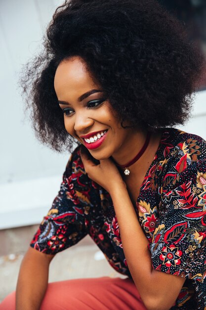 Foto einer lächelnden attraktiven afroen-amerikanisch Frau mit bunter Verfassung und weißen Zähnen