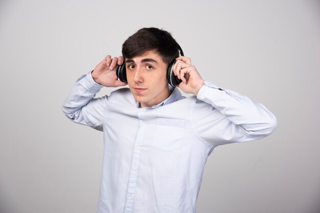 Foto eines jungen Modells, das in drahtlosen Kopfhörern steht und in die Kamera schaut