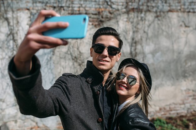 Foto eines jungen schönen Paares, das Selfie auf grauer Wand macht