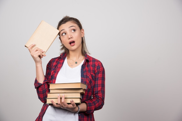 Foto eines nachdenklichen jungen Studenten, der einen Stapel Bücher hält.