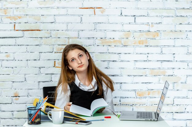 Foto eines Schulmädchens, das sich müde fühlt und ihr Notizbuch hält