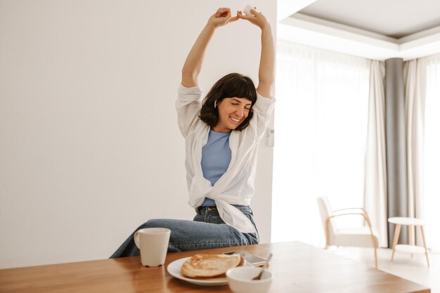 Foto lächelnde Frau Frühstück mit Kaffee und Pfannkuchen