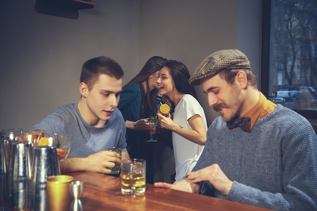 Foto von freudigen Freunden in der Bar oder in der Kneipe, die miteinander kommunizieren