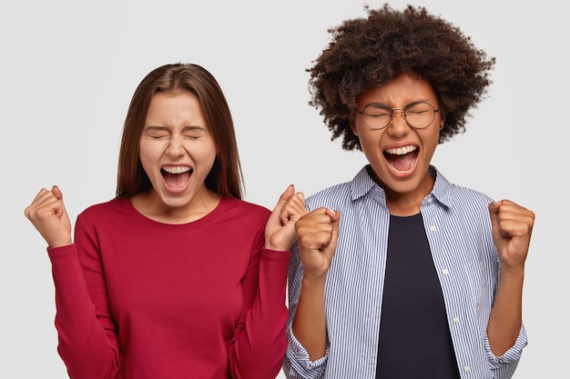 Foto von überglücklichen Frauen gemischter Rassen, die geballte Fäuste heben