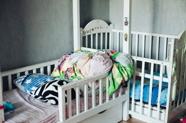 Fotofragment eines Kinderzimmers mit verstreuten Sachen, Kissen und Bettdecken auf den Betten