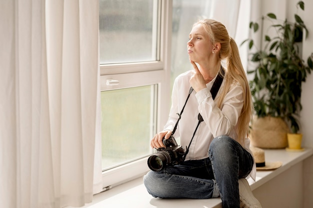 Fotograf, der auf Fensterbank-Fotokunstkonzept sitzt