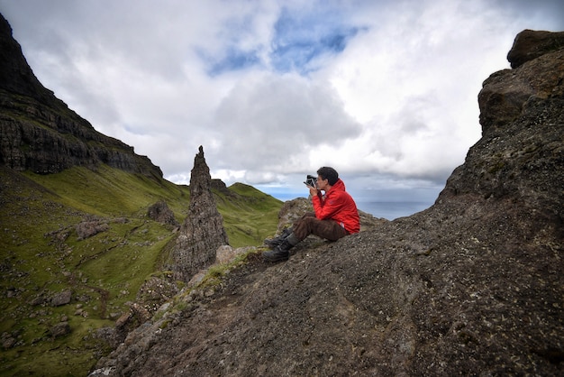 Fotograf, der Fotos macht, die auf einem Felsen eines Berges sitzen