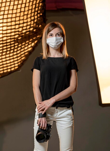 Fotograf, der medizinische Maske in einem Studio trägt