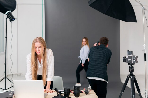 Fotograf mit dem Modell und Frau, die an Laptop von der Ansicht arbeiten