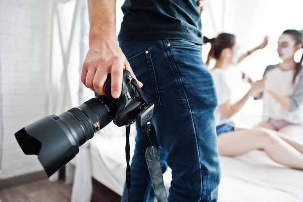 Fotograf schießt Hände hautnah mit DSLR-Kamera und Model posiert im Studio im Hintergrund