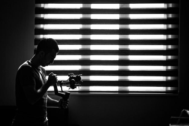 Kostenloses Foto fotograf überprüft seine kamera in der dunkelheit.
