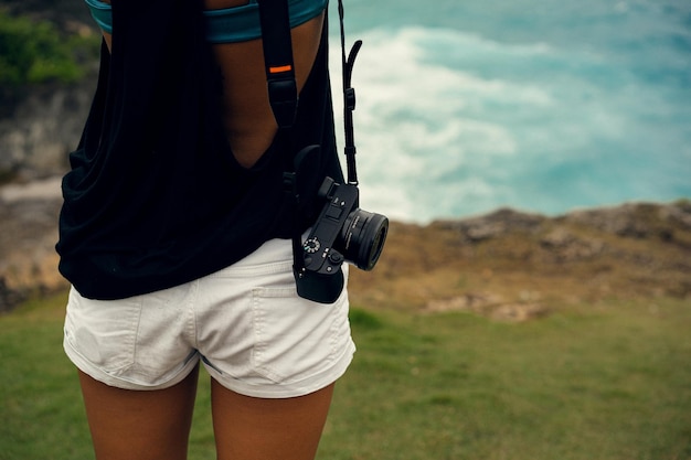 Kostenloses Foto fotografin der jungen frau mit einer kamera am rand einer klippe fotografiert die natur