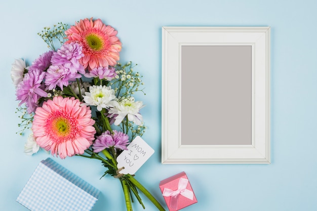Fotorahmen nahe frischen Blumen mit Titel auf Tag nahe Paket, Geschenk und Notizbuch
