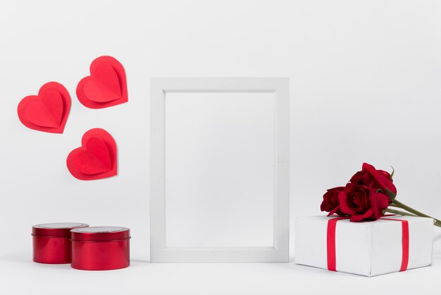 Fotorahmen zwischen Geschenk mit Blumen, Papierherzen und Kästen