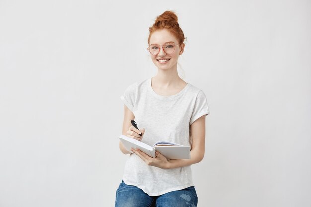 foxy Studentin lächelnd mit Notizbuch.