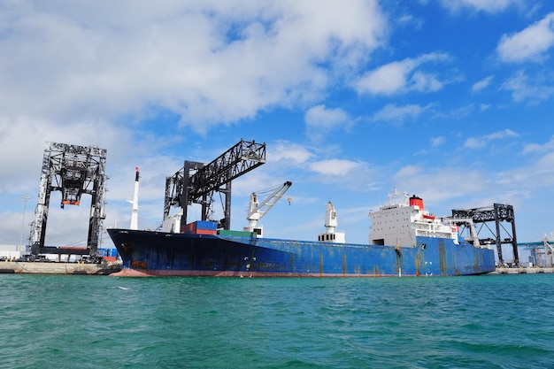 Frachtschiff im Hafen von Miami mit Kran und blauem Himmel über dem Meer.