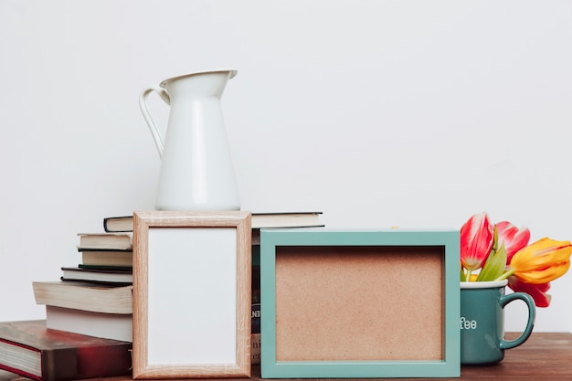 Kostenloses Foto frames in der nähe von blumen und krug auf bücher