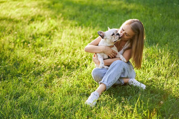 Französische Bulldogge, die Besitzerin im Park küsst