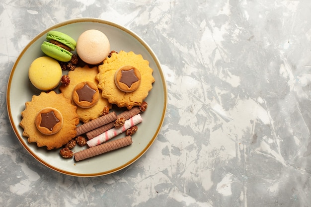 Französische Macarons der Draufsicht mit Kuchen und Plätzchen auf Kekszuckerkuchen des weißen Kekses der weißen Oberfläche