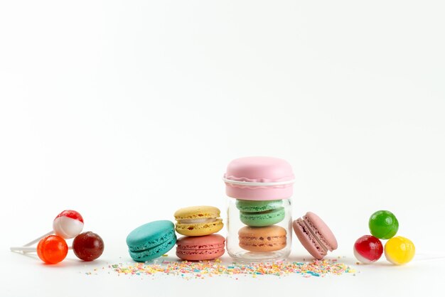 Französische Macarons der Vorderansicht zusammen mit Lutschern auf weißem, süßem Kuchenkekszucker