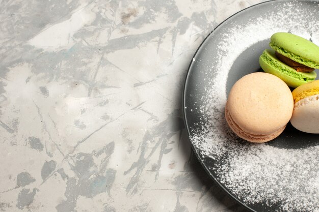 Französische Macarons köstliche farbige Kuchen der oberen Nahansicht innerhalb der Platte auf weißer Oberfläche
