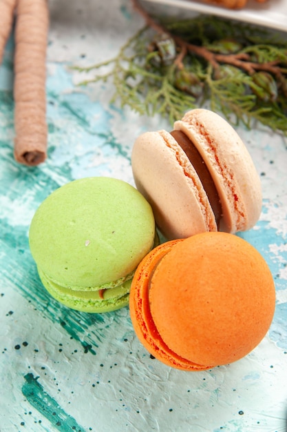 Kostenloses Foto französische macarons köstliche kleine kuchen der vorderansicht auf hellblauer oberfläche