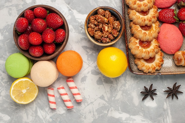 Französische Macarons von oben mit frischen roten Erdbeeren und Keksen auf weißer Oberfläche