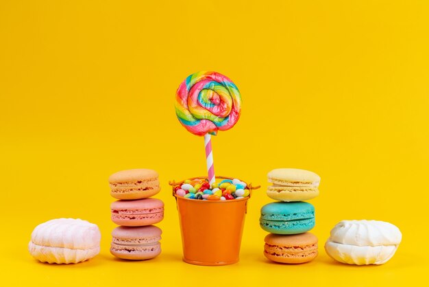 Französische Macarons von vorne mit Baisers und Lutschern auf gelben Kuchenkeks-Süßigkeiten