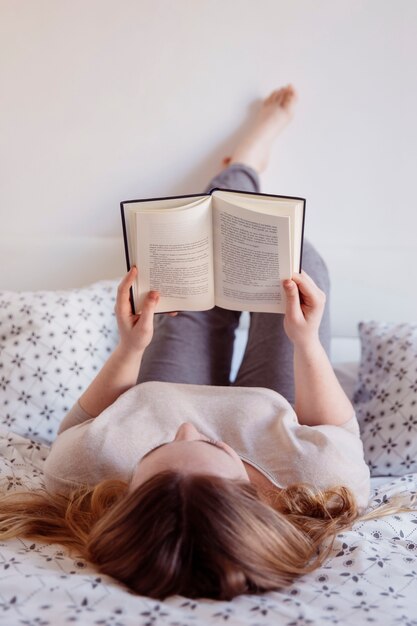 Frau am Bett liegen und lesen