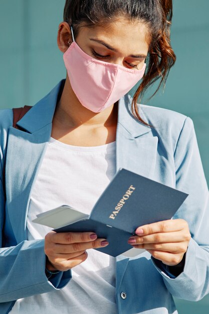 Frau am Flughafen mit medizinischer Maske, die ihren Pass überprüft