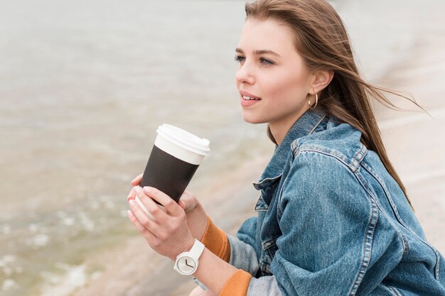 Frau am Meer mit Kaffee