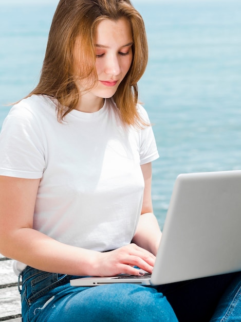 Frau am Strand arbeitet am Laptop