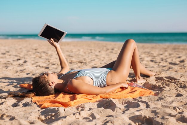 Frau am Strand mit Tablette