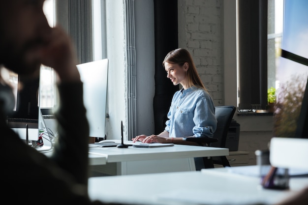 Frau arbeiten im büro mit computer. zur seite schauen.