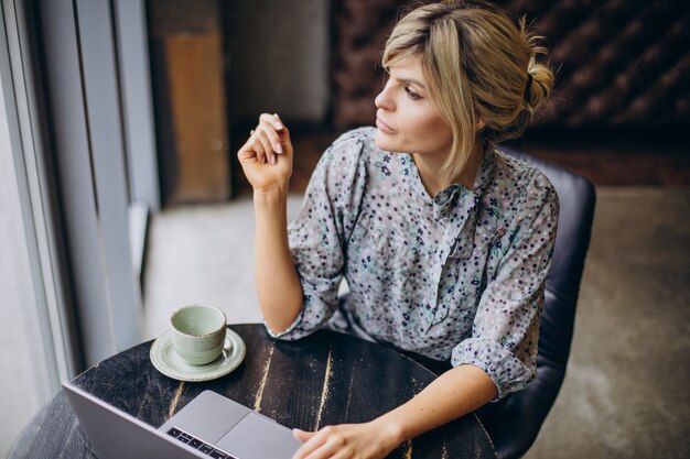 Frau arbeitet am Computer und trinkt Kaffee