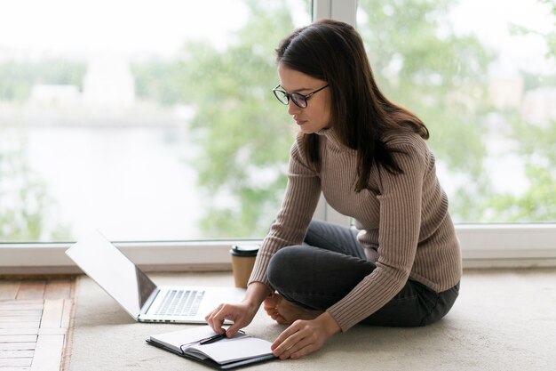 Frau arbeitet an ihrem Laptop auf dem Boden