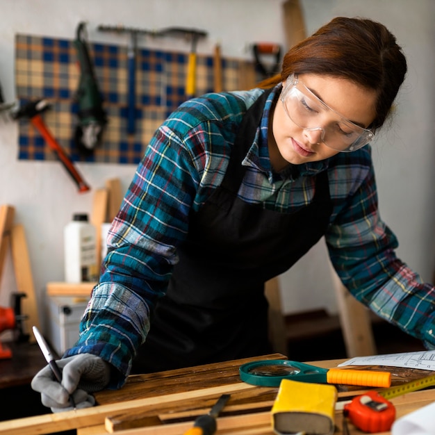 Frau arbeitet in der Werkstatt mit Maßband