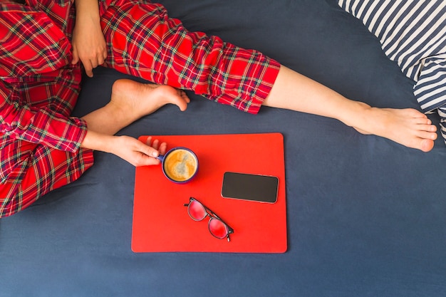 Frau auf Bett mit Kaffee und Smartphone