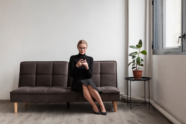 Frau auf Couch unter Verwendung des Mobiles