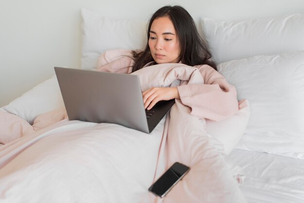 Frau auf dem Bett mit Laptop