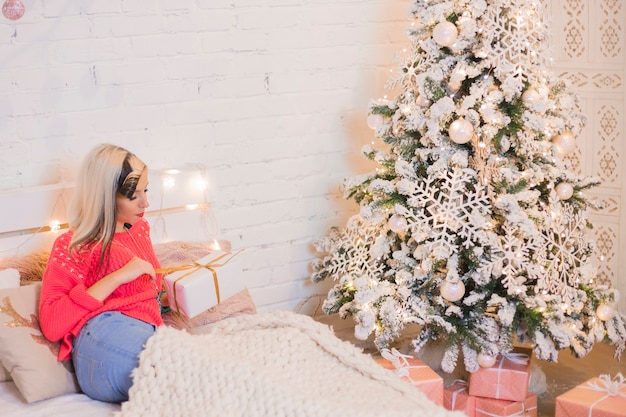 Frau auf dem Bett neben Weihnachtsbaum