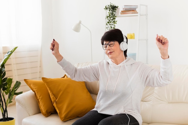 Frau auf dem Sofa genießt Musik auf Kopfhörern