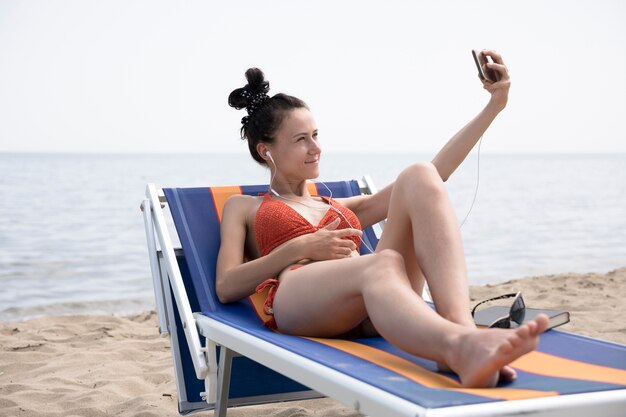 Frau auf dem Strandstuhl, der ein selfie nimmt